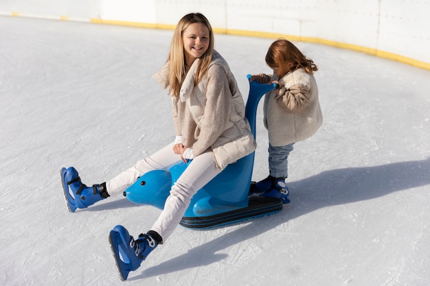 Kostenloses Foto volle aufnahme glückliche frau mit kind an der eisbahn