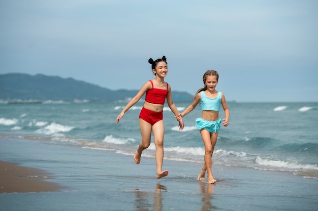 Kostenloses Foto volle schussmädchen, die auf strand laufen