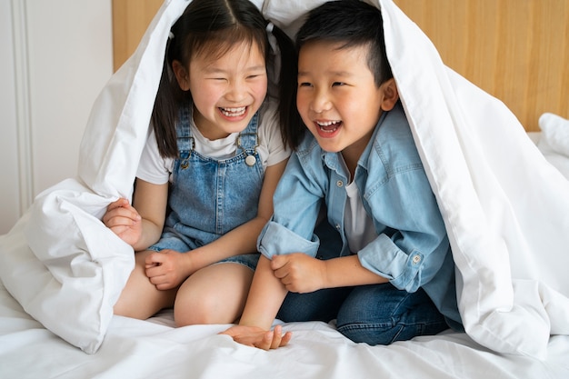 Kostenloses Foto voller schuss kinder sitzen unter decke