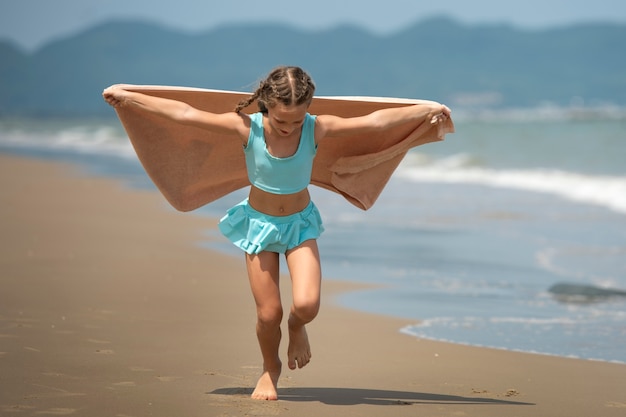 Kostenloses Foto vollschussmädchen, das am strand läuft