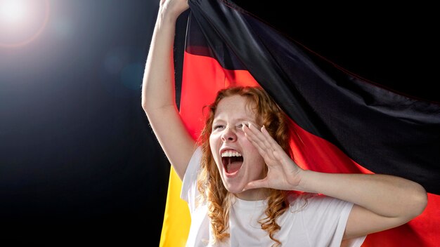 Vorderansicht der jubelnden Frau, die deutsche Flagge hält