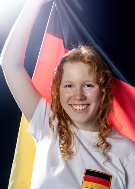 Vorderansicht der lächelnden Frau, die deutsche Flagge hält