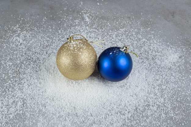 Kostenloses Foto weihnachtsbaumdekorkugeln sitzen auf einem haufen kokospulver auf marmoroberfläche