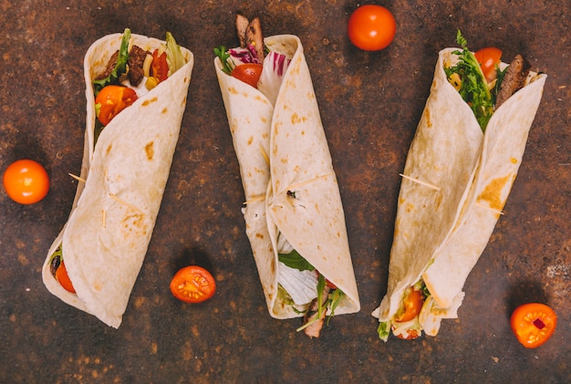 Kostenlose Foto wickeln sie mexikanische rindfleischtacos mit tomaten auf rostigem hintergrund ein