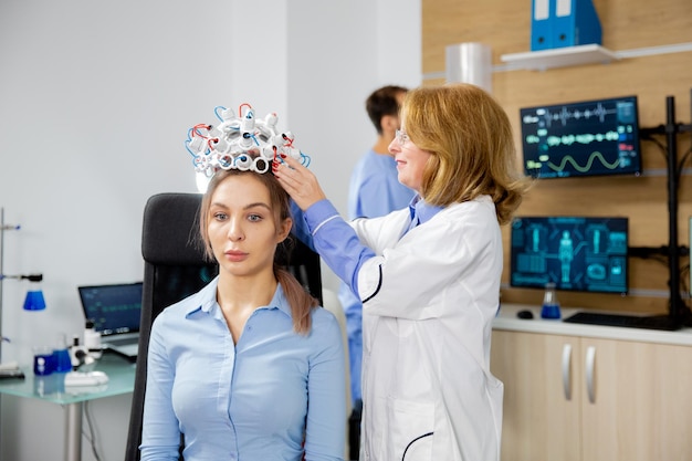 Kostenloses Foto wissenschaftlerin, die einem weiblichen patienten ein gerät zum scannen von gehirnwellen anlegt. klinische studie zur gehirnaktivität