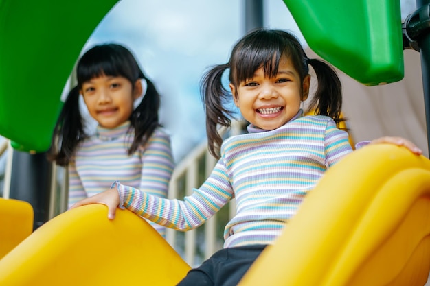 Kostenloses Foto zwei mädchen spielen rutschen auf dem spielplatz. selektiver fokus