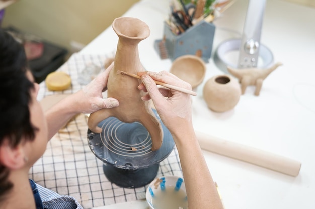 Foto a mulher esculpe o vaso da argila pelas mãos fechadas no estúdio artístico