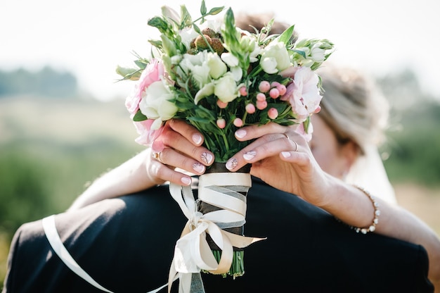 A noiva e o noivo com um buquê de casamento, segurando as mãos e levantando-se na cerimônia de casamento