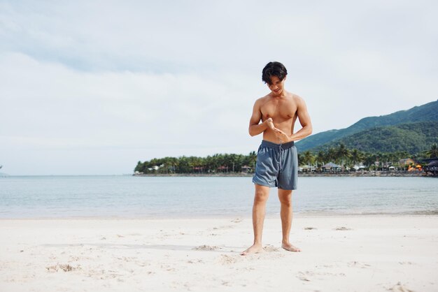 Foto aktiver asiatischer athlet, der am strand läuft, mit einem muskulösen und fitten körper, der die freiheit genießt und