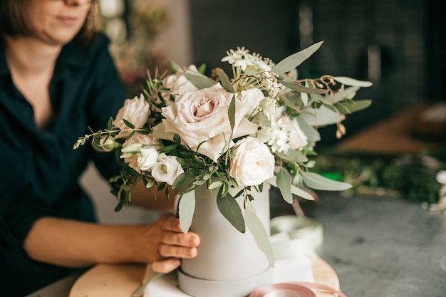 Ambiente de trabalho em floricultura, florista está trabalhando na criação de buquê de rosas brancas frescas. Hobby ou conceito de pequena empresa