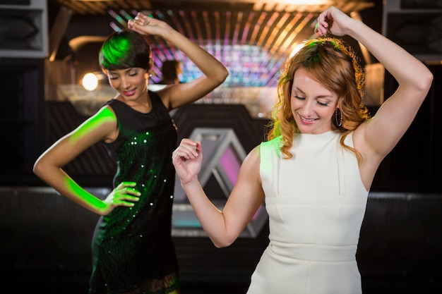 Amigos do sexo feminino dançando na pista de dança a sorrir