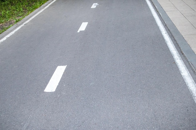 Aproximação de uma estrada de asfalto com uma linha de marcação intermitente e grama ao lado da estrada Foco seletivo fotografia em preto e branco