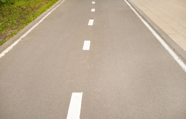 Aproximação de uma estrada de asfalto com uma linha de marcação intermitente e grama ao lado da estrada Foco seletivo fotografia em preto e branco