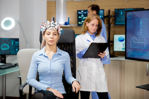 Foto arzt, der in der zwischenablage die entwicklung des patienten während des neurologie-headset-tests notiert. gehirntest