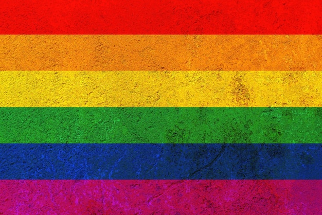 Bandeira do arco-íris contra uma parede de ferro enferrujado. Bandeira LGBT pintada em uma parede de ferro enferrujado