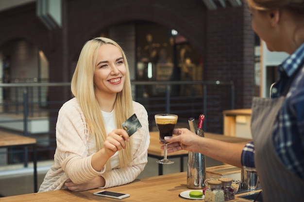 Barista nimmt Kreditkarte vom Kunden, um Getränke an der Cafétheke zu bezahlen. Kleinunternehmen, Berufsleute, Zahlungs- und Servicekonzept, Kopierraum