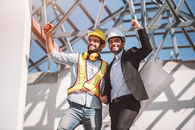 Bauingenieure und Bauarchitekten arbeiten auf der Baustelle mit Tablets und Blaupausen für die Planung eines neuen Teamwork-Konzepts für Baustellenzusammenarbeit