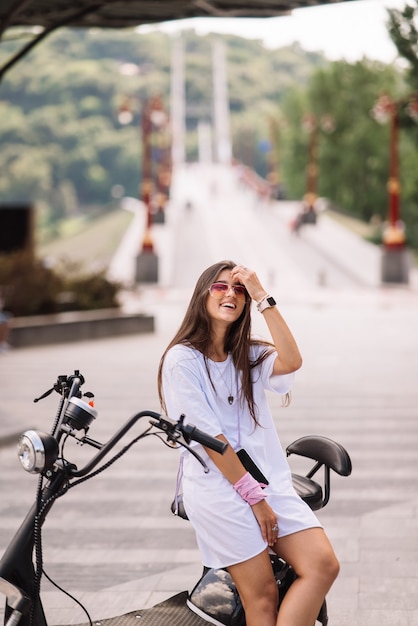 Foto bela jovem e uma scooter elétrica, transporte ecológico