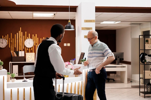 Foto bellboy hilft einem älteren mann mit dem gepäck