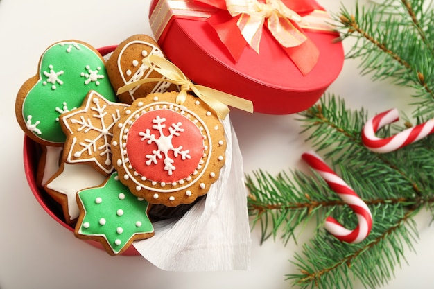 Caixa com biscoitos de gengibre, doces e galho de árvore do abeto na mesa branca