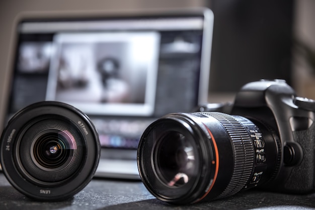 Câmera profissional e close-up de lente na área de trabalho de um fotógrafo em um fundo desfocado. O conceito de equipamento profissional para foto e vídeo.