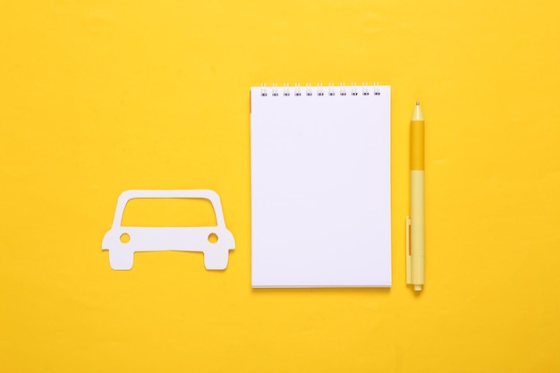 Carro de corte de papel e notebook em fundo amarelo