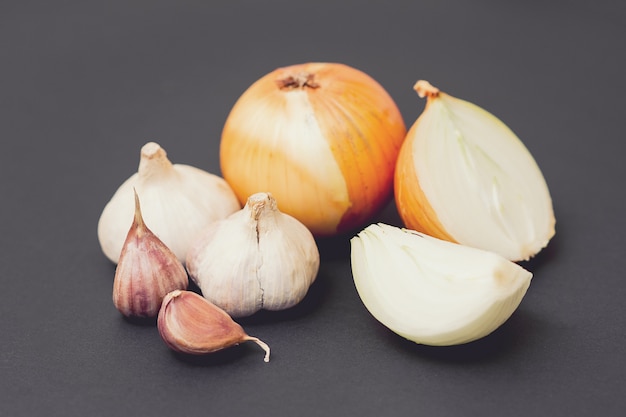 Foto cebola e alho cru com casca em uma mesa preta