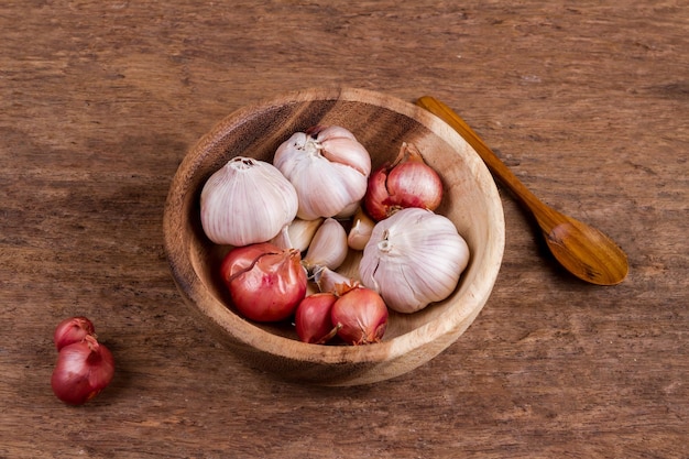 Foto cebola e alho em uma tigela de madeira na velha vindima de fundo de madeira