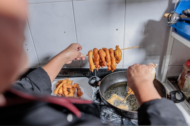 Chef latino sênior do Peru cozinhando picarones em cozinha profissional para pequenas empresas