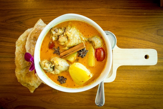 Chicken Massaman und Roti auf Holzplatte auf Holztisch.