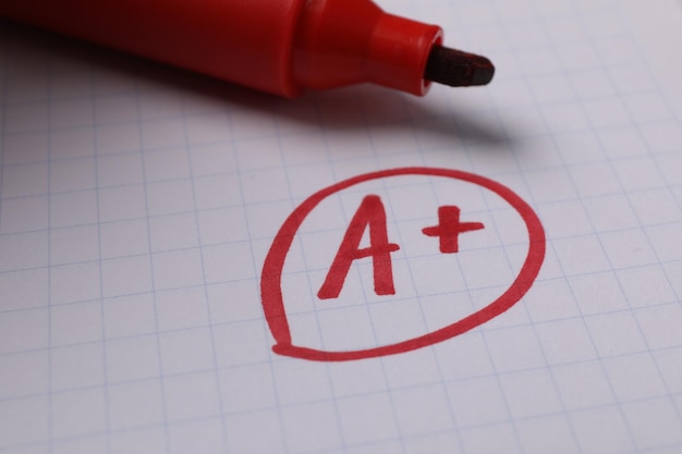 Foto classe escolar letra vermelha a com símbolo mais em papel de caderno e marcador de close-up