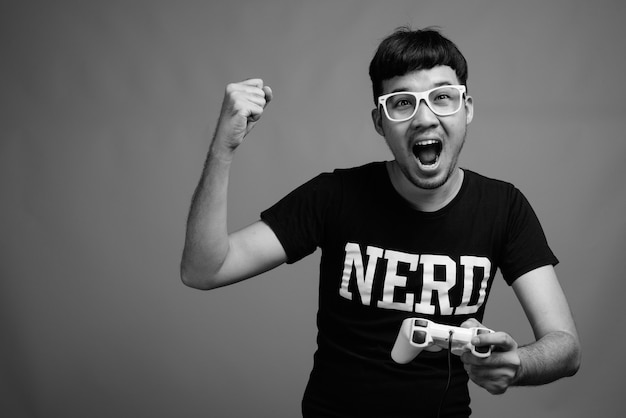 Foto close de um jovem nerd asiático usando óculos enquanto joga