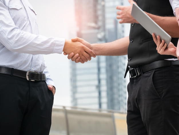 Close-up de handshaking de pessoas de negócios sobre fundo de cidade. Reunião ao ar livre de parceria de negócios