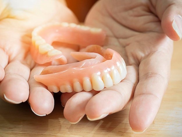 Close-up de mãos femininas segurando dentadura de nylon flexível