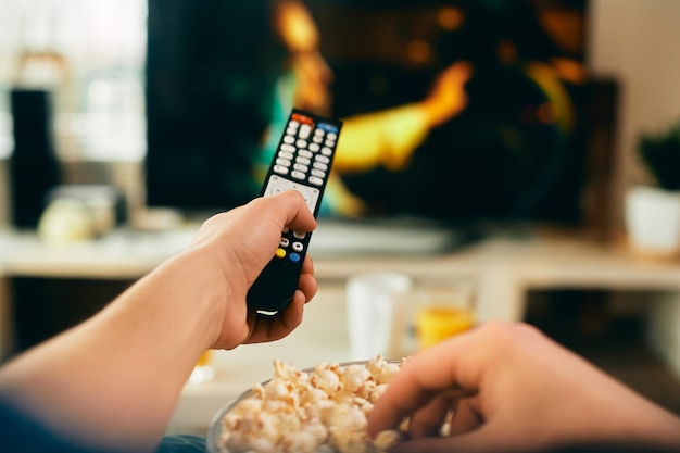 Closeup de homem assistindo filme na TV e comendo pipoca em casa