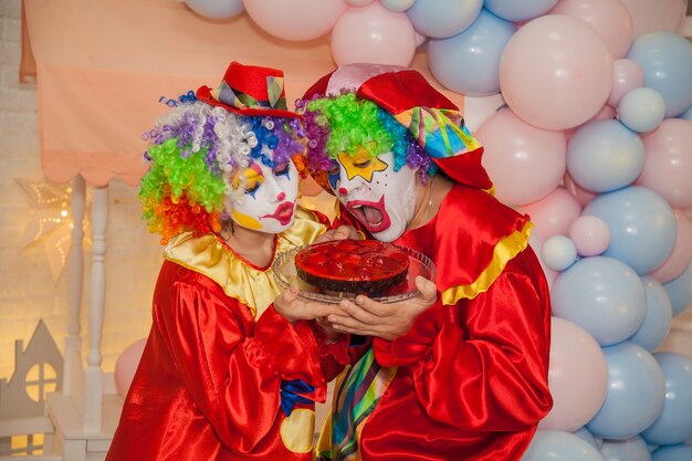 Foto clownjunge mit clownmädchen streiten sich um einen leckeren kuchen