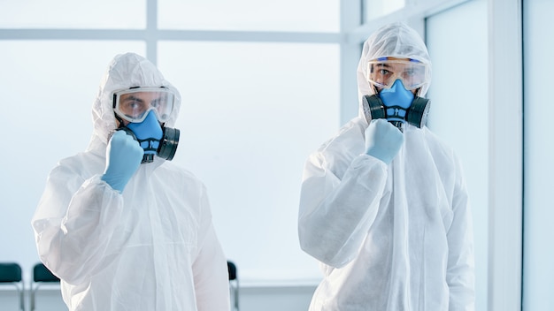 Foto colegas em trajes de risco biológico em pé no laboratório