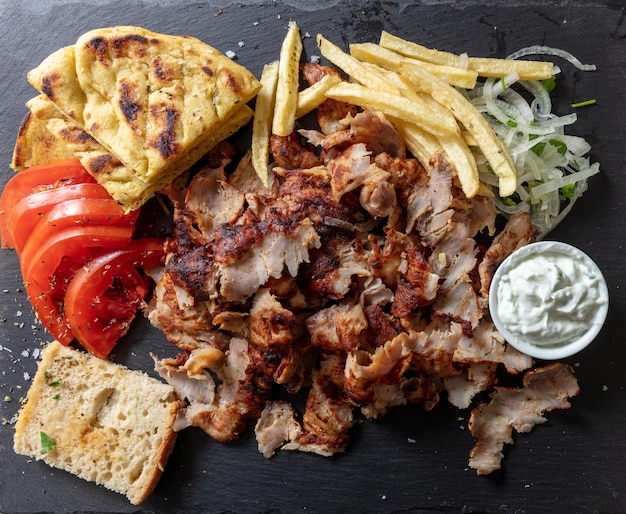 Comida de carne tradicional de giro grego sobre cabeça preta Carne de prato étnico cortado pão pita e tzatziki