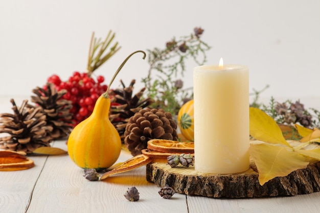 Cones de velas e abóboras decorativas e folhas amarelas de outono em uma mesa de madeira branca composição de outono decoração de conforto