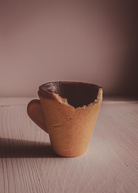 Foto copo comestível mordido feito de biscoitos em um fundo claro pratos comestíveis copo feito de biscoitos