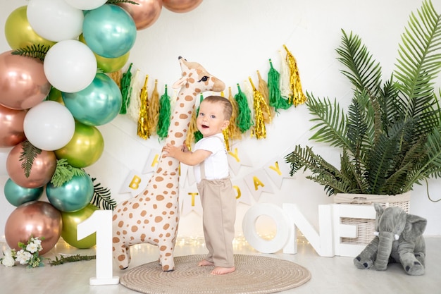 Foto der süße kleine junge feiert seinen ersten geburtstag auf dem hintergrund von leuchtend bunten luftballons und festlichen requisiten den ersten kinderurlaub