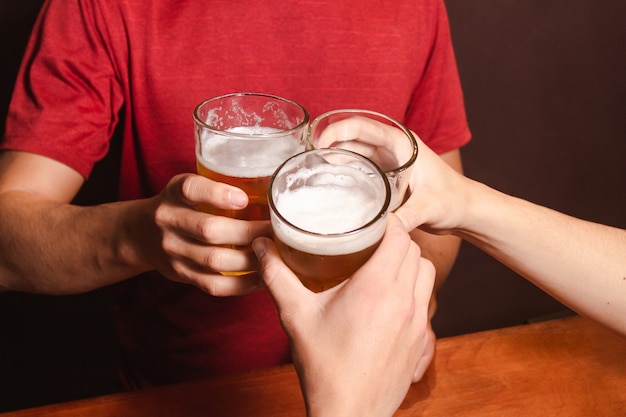 Foto detail der leute, die ihre gläser mit bier an der bar anstoßen.