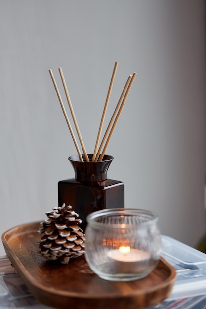 Foto difusor de cana de aroma cone de pinheiro e vela em casa