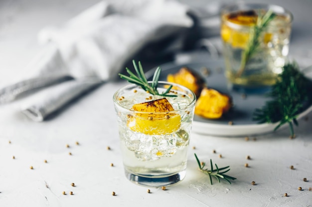 Foto dois copos de limão carbonizado, alecrim e coentro, gin e tónico, é um coquetel refrescante perfeitamente equilibrado, com um fundo claro de perto.