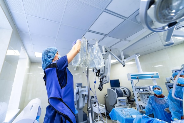 Foto doktorfrau in medizinischer maske und sterilen handschuhen, die eine pipette vorbereiten. hintergrund der chirurgischen operation.