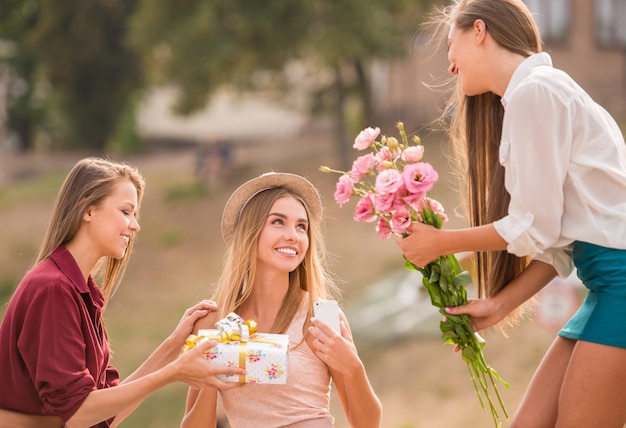 Drei schöne junge Frauen mit Blumen im Freien