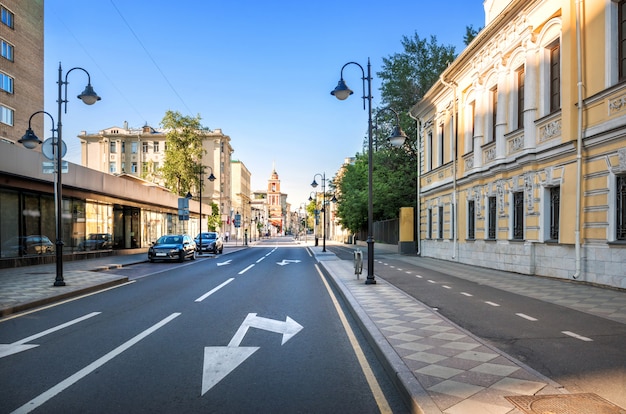 Edifícios antigos e modernos e a torre do sino da Igreja da Trindade na rua Pyatnitskaya em Moscou sob os raios do sol da manhã de verão