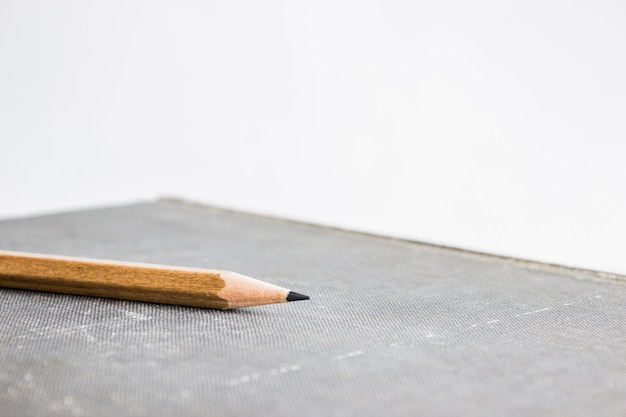 Foto ein hölzerner bleistift auf einem buch über der hellen wand mit kopierplatz