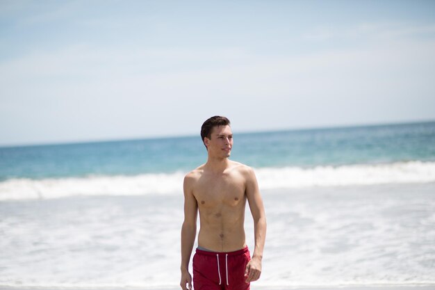 Foto ein junger mann steht am strand gegen den himmel