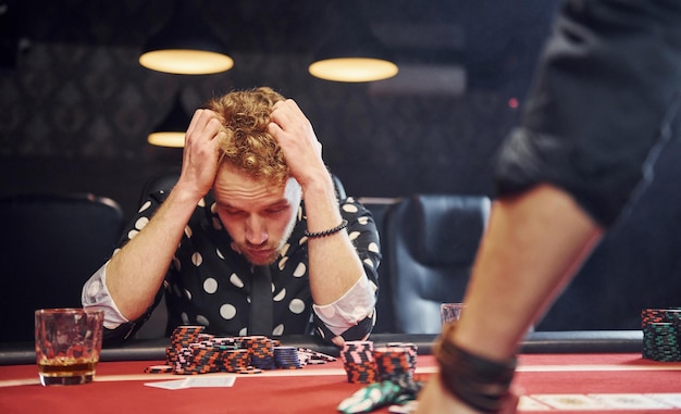 Foto ein mann sitzt im casino und fühlt sich schlecht, weil er ein pokerspiel verloren hat.